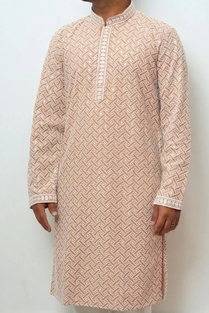 Man wearing a patterned kurta with white pants against a plain background