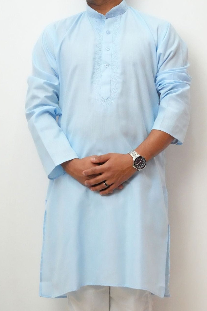 Man wearing a light blue kurta with white pants against a white background