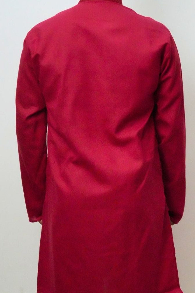 Person wearing a red kurta with white pants against a plain background